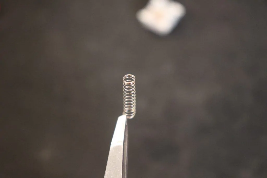 mechanical keyboard switch spring being held by tweezers