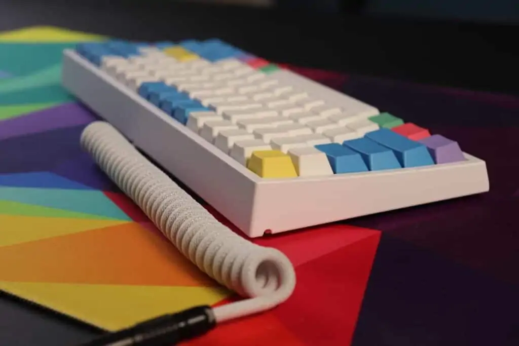 mechanical keyboard with coiled cable on a deskmat.