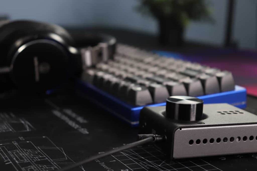 Angled view of a keyboard, mouse, and headphone amp on a desk